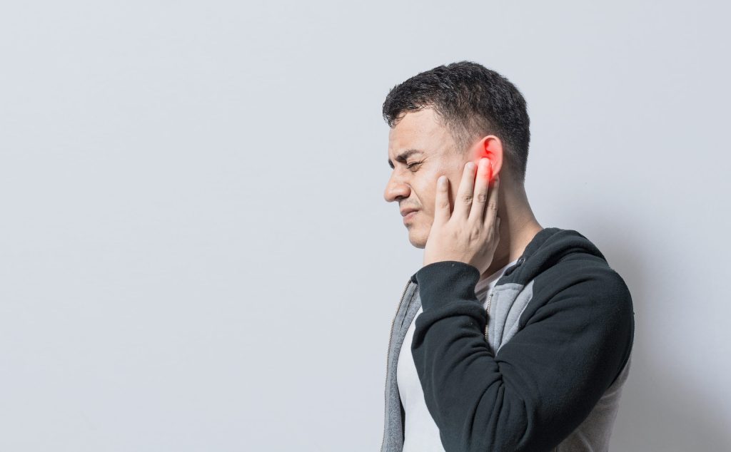 person with otitis tinnitus person with ear pain isolated background suffering man massaging his ear isolated scaled e1691587804540